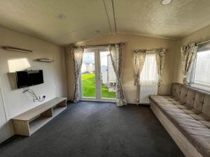 a living room with a couch and a tv at Superb 8 Berth Caravan For Hire At St Osyth Beach In Essex Ref 28055cw in Clacton-on-Sea