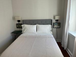 a bed with white sheets and pillows in a bedroom at The Trinity Cottage in Manayunk, Walk to Main Street and Train in Philadelphia