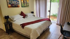 1 dormitorio con 1 cama con sábanas blancas y almohadas rojas en SABLE INN B&B, en Modimolle