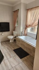 a bathroom with a tub and a toilet and a sink at SABLE INN B&B in Modimolle