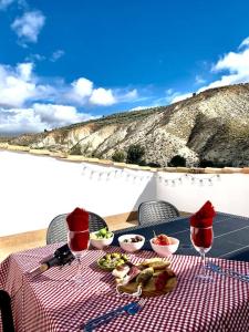 una mesa de picnic con comida y copas de vino y vistas a la montaña en Casa Rural Caballeriza en Hinojares