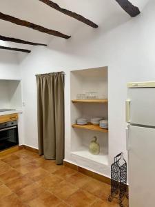 una cocina con nevera y estanterías con platos en Casa Rural Caballeriza en Hinojares