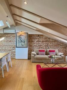 a living room with a couch and a brick wall at Les Toits du Capitole - Loft de standing 60 m2 - Parking en option in Toulouse