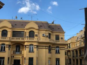 un grand bâtiment jaune avec des oiseaux sur le toit dans l'établissement Rhala Hostel Egypt, au Caire