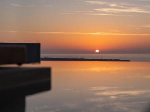 a sunset over the water with the sun in the sky at Santo Mine Oia Suites in Oia