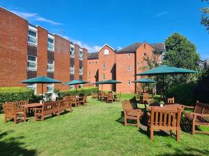 una fila de mesas y sillas de madera con sombrillas en Holiday Inn Farnborough, an IHG Hotel en Farnborough