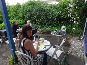 een vrouw aan een tafel in een patio bij Casa Mundo Bed & Breakfast in Vejle