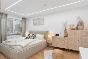 a white bedroom with a bed and a dresser at ANYTIME - Apartments in Langenargen in Langenargen