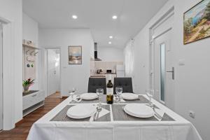 uma sala de jantar branca com uma mesa com copos de vinho em Apartment ART em Brodarica