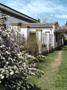 a white fence and flowers in front of a house at Hostería Casa de Campo in Chascomús
