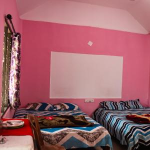 two beds in a room with a pink wall at Munnar green portico cottage in Munnar