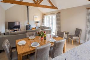 a dining room and living room with a wooden table and chairs at Filby Barn by Big Skies Cottages in Docking