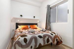 1 dormitorio con 1 cama con almohadas de color naranja y ventana en Arena Negra, en Telde