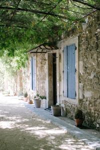 um antigo edifício de pedra com uma porta azul e vasos de plantas em Charming Loft in the countryside of Althen des Paluds em Althen-des-Paluds