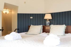 1 dormitorio con 1 cama con almohadas blancas y lámpara en Grand Hotel Saltsjöbaden, en Saltsjöbaden