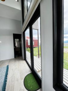 Habitación con ventanas grandes y alfombra verde. en Cabañas Julián Elias, en Puerto Natales