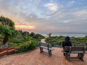 a person sitting on a bench looking at the ocean at Margate Beach Club in Margate