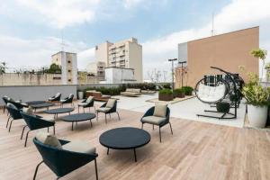 a rooftop patio with chairs and tables on a building at Studio de Luxo de Alta Qualidade in Sao Paulo
