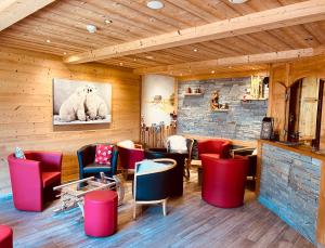 un restaurant avec des chaises rouges et bleues et un mur en briques dans l'établissement Hameau des Prodains - Hôtel, à Morzine