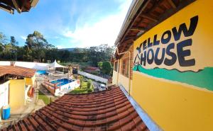 une maison jaune avec un panneau sur son côté dans l'établissement Hostel Yellow House MG, à Itamonte
