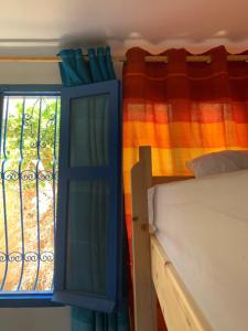 een slaapkamer met een bed en een raam bij Hostel The Endless House Anchor point in Taghazout
