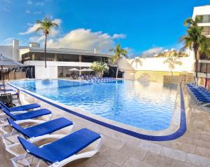 uma grande piscina com cadeiras azuis e palmeiras em Sol Caribe San Andrés All Inclusive em San Andrés