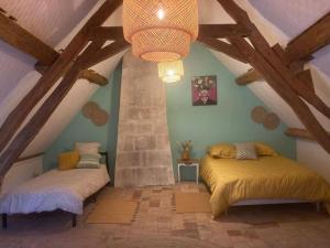 2 łóżka w pokoju na poddaszu z drewnianymi belkami stropowymi w obiekcie Longère de charme w mieście Saint-Cyran-du-Jambot