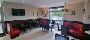 a dining room with red chairs and a table and a tv at Hotel le Bellevue in Guer