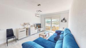 uma sala de estar com um sofá azul e uma televisão em Casa Claveles - A Murcia Holiday Rentals Property em Santiago de la Ribera