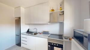 uma pequena cozinha com armários brancos e um lavatório em Casa Claveles - A Murcia Holiday Rentals Property em Santiago de la Ribera