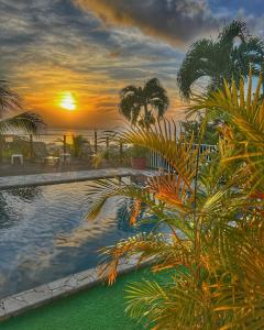 puesta de sol sobre una piscina con palmeras en Résidence Paradis Tropical en Basse-Terre