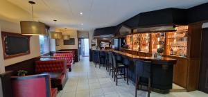 a bar in a restaurant with red chairs at Hotel le Bellevue in Guer