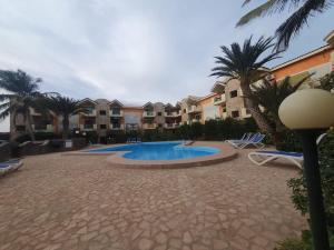 a swimming pool with chairs and palm trees and condos at CosmoCom Moradias Residence Capo Verde in Santa Maria