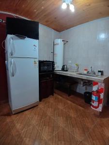 a kitchen with a white refrigerator and a counter at Cabañas Las Delicias in Salta