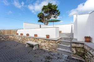 a stone wall with a bench and an umbrella at Cornish Views in Camborne