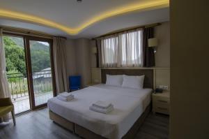 a bedroom with a large white bed and a window at Funda Hotel in Göcek