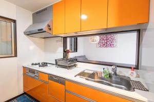 a kitchen with orange cabinets and a sink at O・KA・E・RI in Osaka
