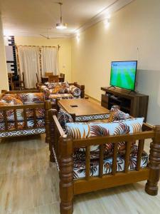 a living room with couches and a flat screen tv at Linda's Little Lincoln in Watamu
