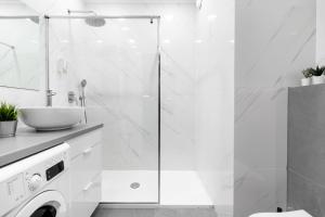 a white bathroom with a shower and a sink at Golden Apartments Warsaw - Luxury And Bright Apartment - Siedmiogrodzka 3 in Warsaw