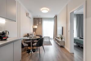 a kitchen and living room with a table and chairs at Golden Apartments Warsaw - Luxury And Bright Apartment - Siedmiogrodzka 3 in Warsaw