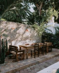 a wooden table and chairs and a wall with trees at Casa Mezcla - Bed & Breakfast in Mérida +17 photos