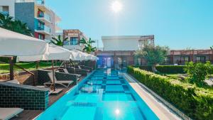 a swimming pool with chairs and umbrellas at a hotel at Feniks Priority Hotel in Okurcalar