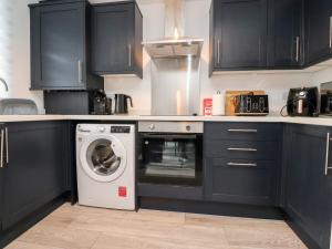 a kitchen with black cabinets and a washing machine at 3 Thrimby Court in Morecambe