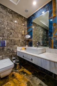 W łazience znajduje się umywalka, toaleta i lustro. w obiekcie Feniks Otel w mieście Okurcalar