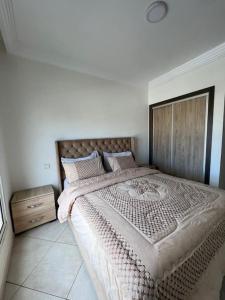 a bedroom with a large bed with a wooden headboard at Appartement Chaleureux et Cosy Proche De sortie autoroute in Mohammedia