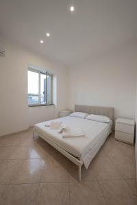 a white bedroom with a bed and a window at Capodichino Airport Home By Dimorra in Naples