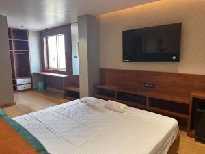 um quarto com uma cama e uma televisão de ecrã plano em V HOTEL em Brahmapur