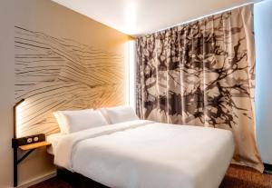 1 dormitorio con cama blanca y pared en B&B HOTEL Besançon Valentin, en Besançon