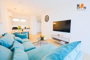 een woonkamer met blauwe banken en een flatscreen-tv bij Westin House Resort by MS Pro in Kołobrzeg