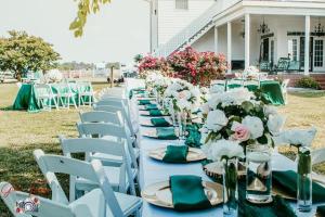a row of white tables with green napkins and flowers at The Barn Apartment at Parkton Place in Hope Mills